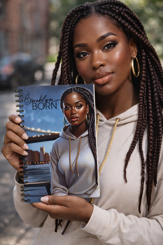 Woman holding a notebook with a cover featuring another woman and 'Brooklyn Born' text.