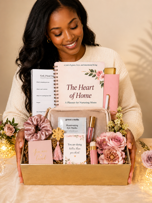 Woman holding a gift box with 'The Heart of Home' planner and other items.